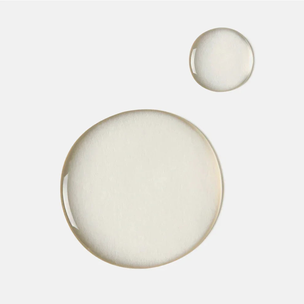Clear mandelic acid cleanser liquid drops on white background, acne skincare texture