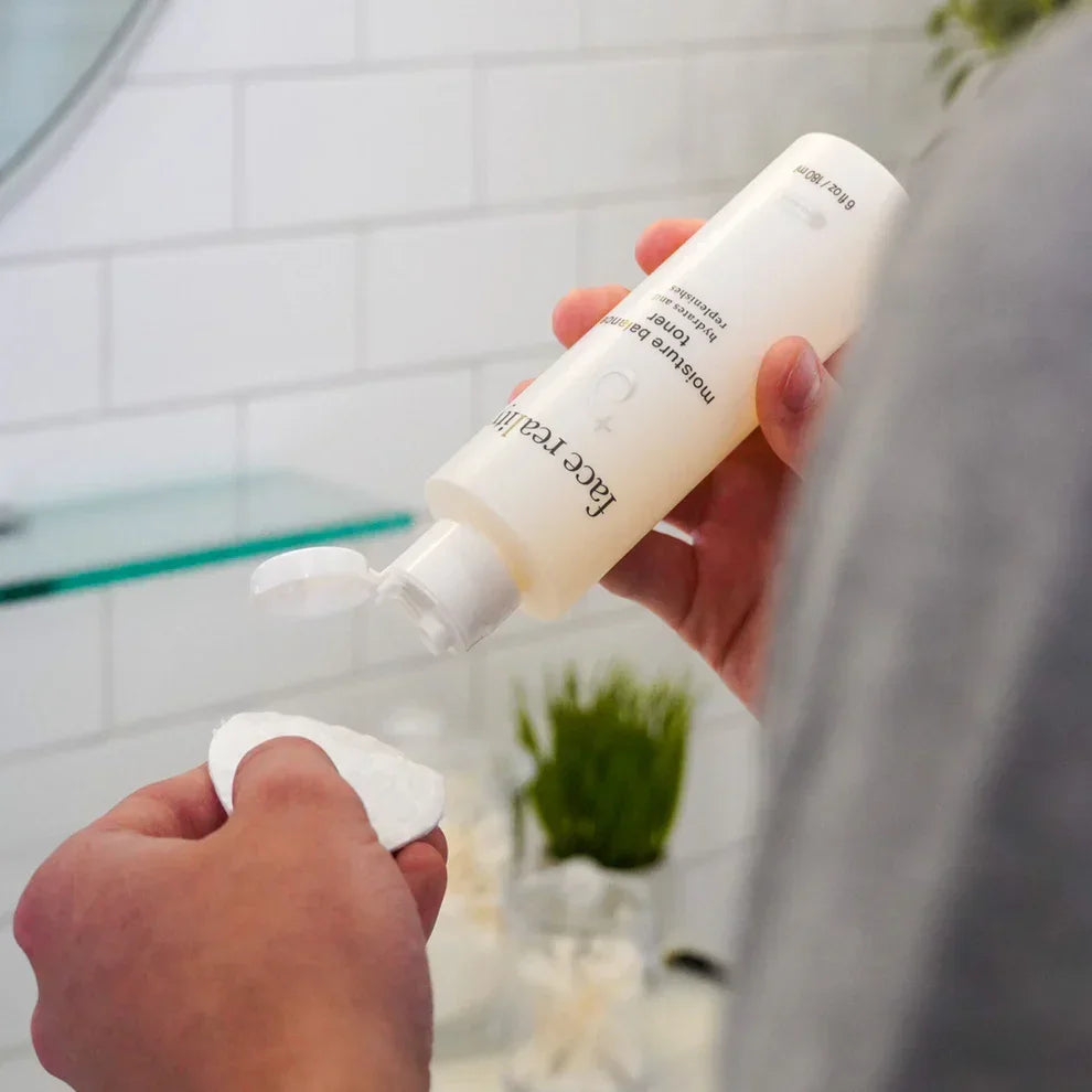 Applying Moisture Balance Toner to cotton pad in a modern bathroom setting