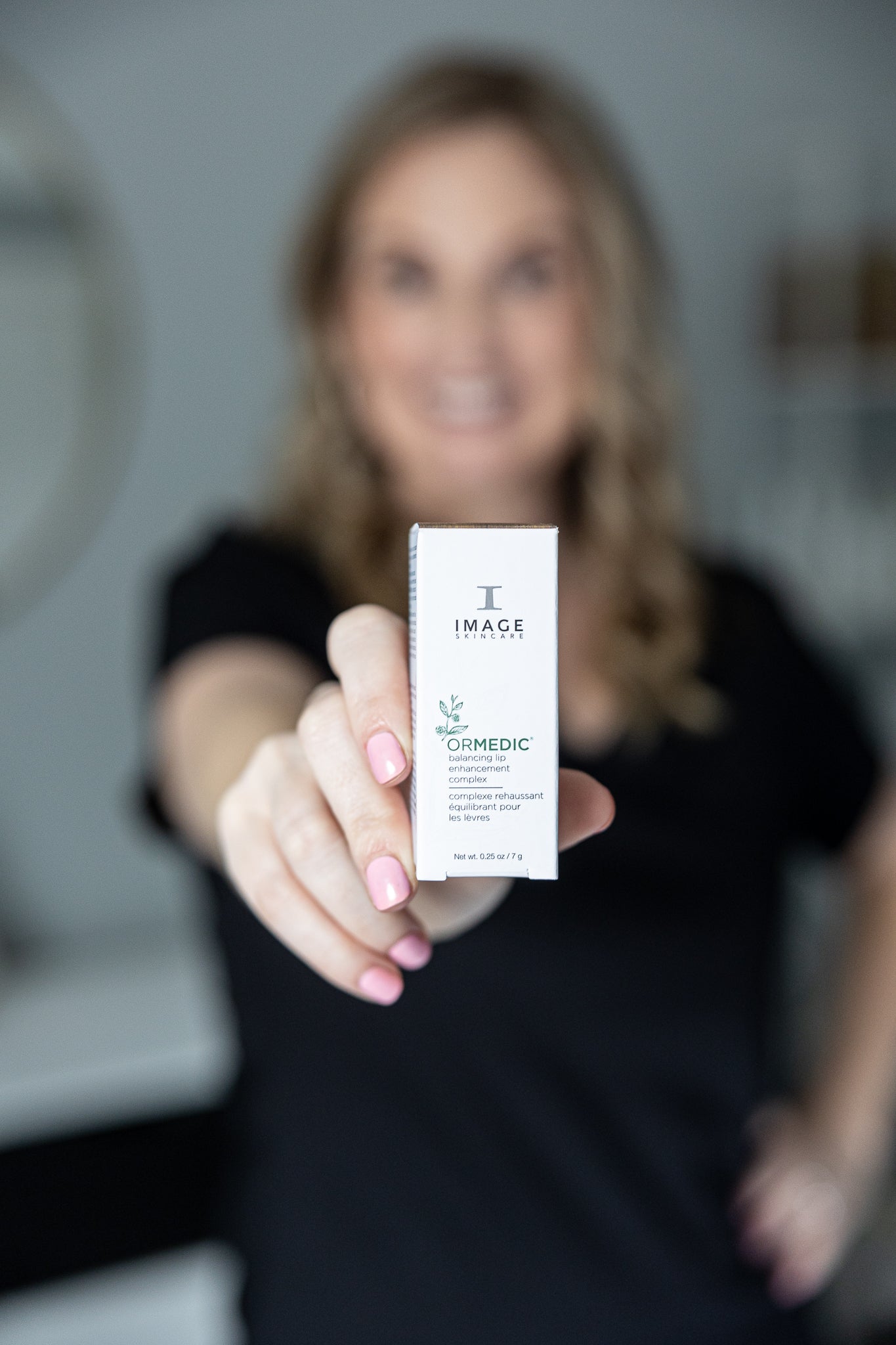 Person holding a skincare product box with a blurred background
