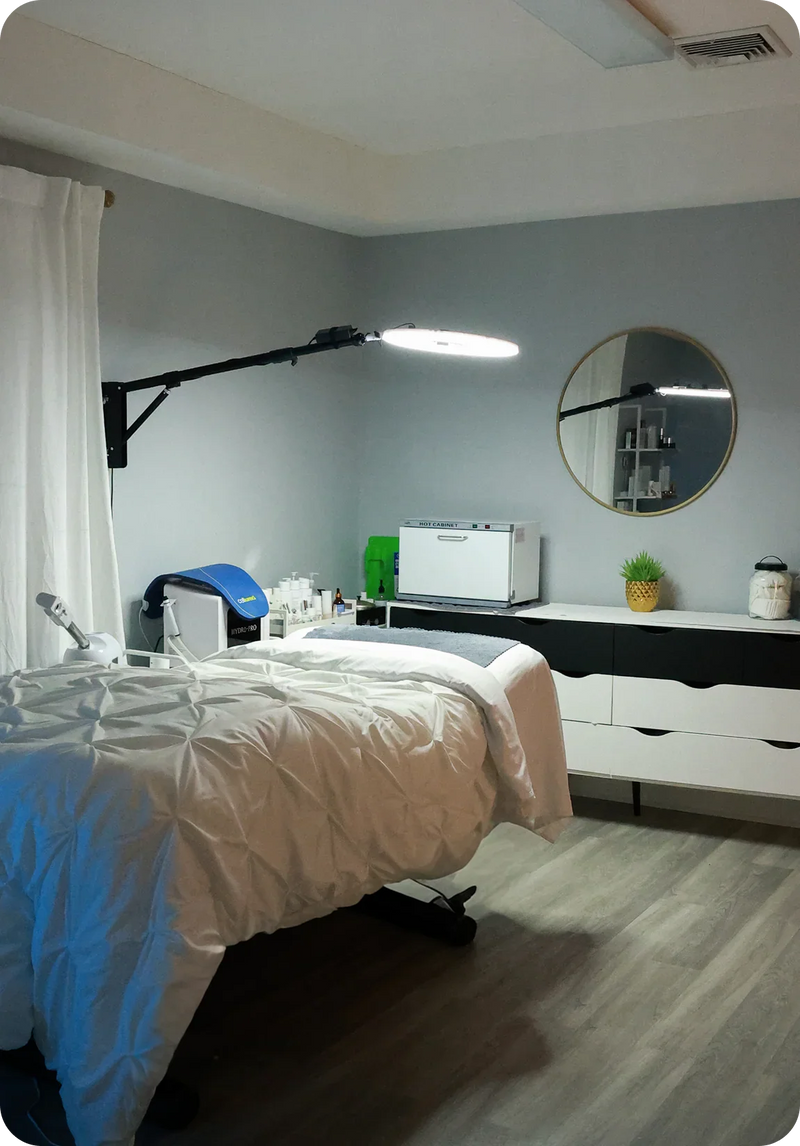 Modern facial treatment room with spa bed, skincare equipment, and bright lighting