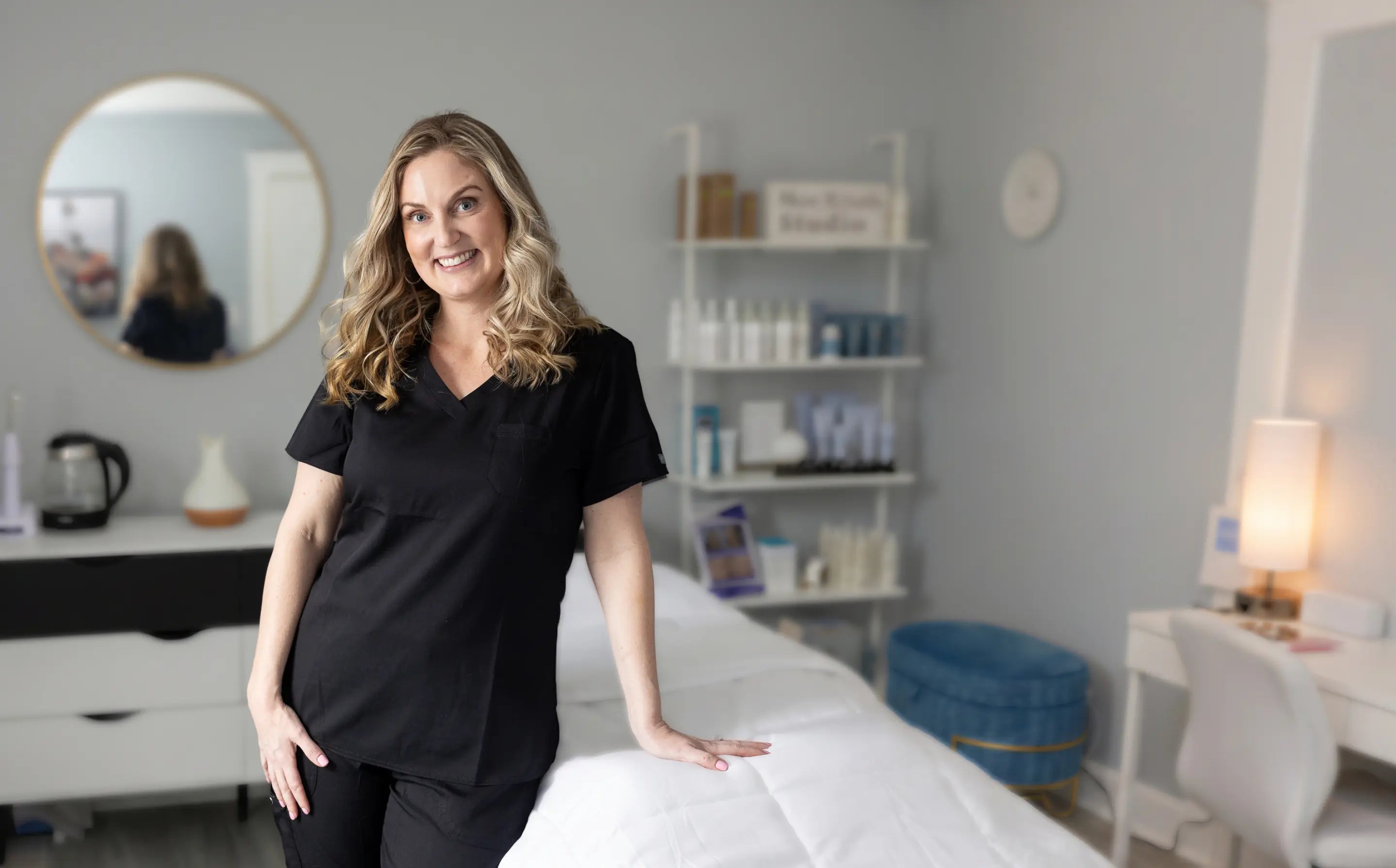 Woman in a black outfit standing in a room with skin care equipment.