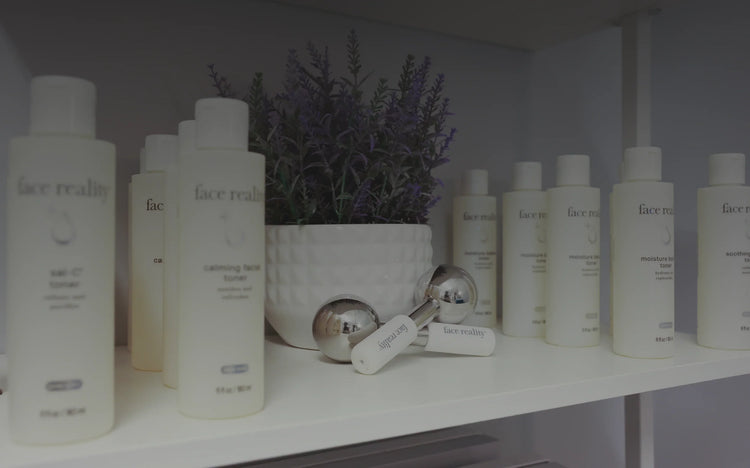 Skincare products and facial rollers on a shelf with lavender decor, featuring Face Reality toner bottles.