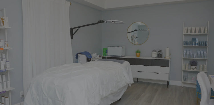 Modern skincare treatment room with facial bed, mirror, and shelves of skincare products
