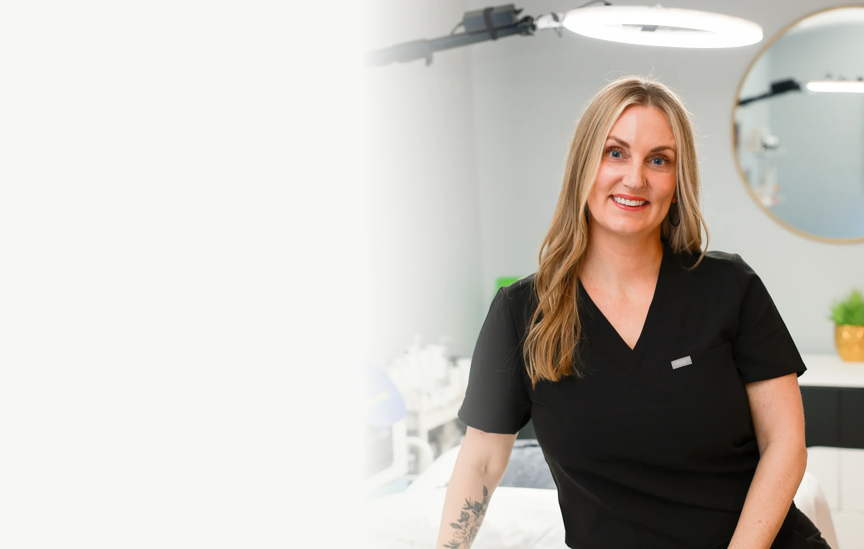 Smiling esthetician in black uniform in a modern skincare treatment room